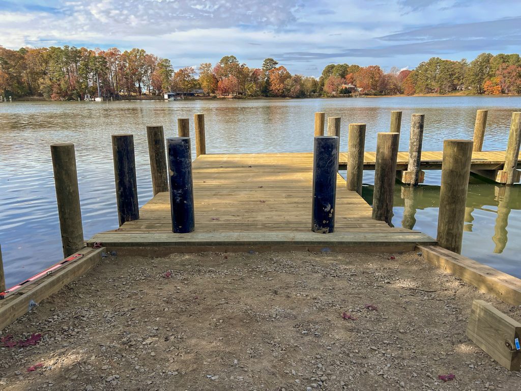 New pier and pilings at a shoreline landing on a wide river in the fall, built by Early Marine Construction
