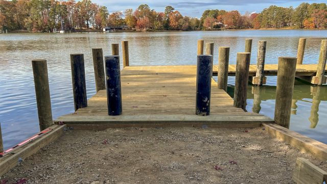 New pier and pilings at a shoreline landing on a wide river in the fall, built by Early Marine Construction