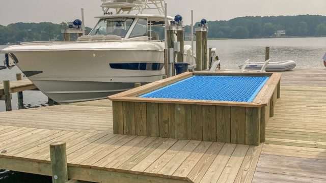New pier with a built in net hammock beside a sportfishing boat on a lift, built by Early Marine Construction