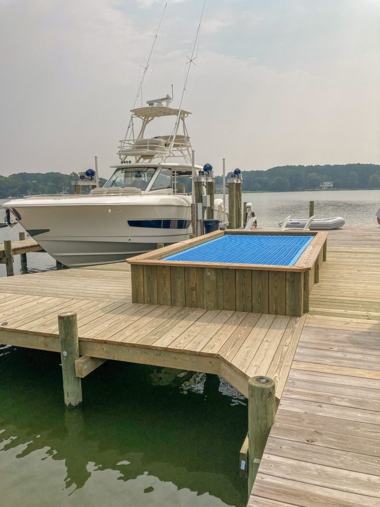 New pier with a built in net hammock beside a sportfishing boat on a lift, built by Early Marine Construction